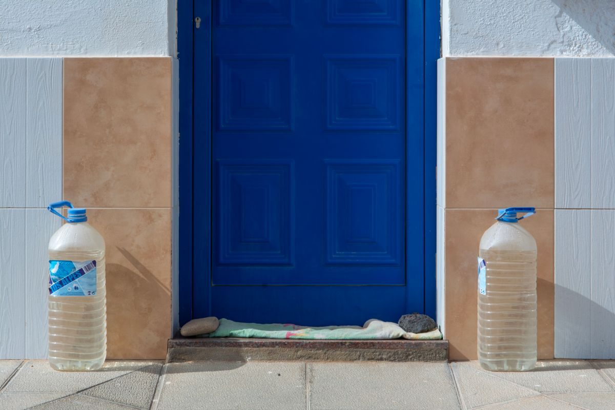 Two plastic water containers set on either side of a blue door.