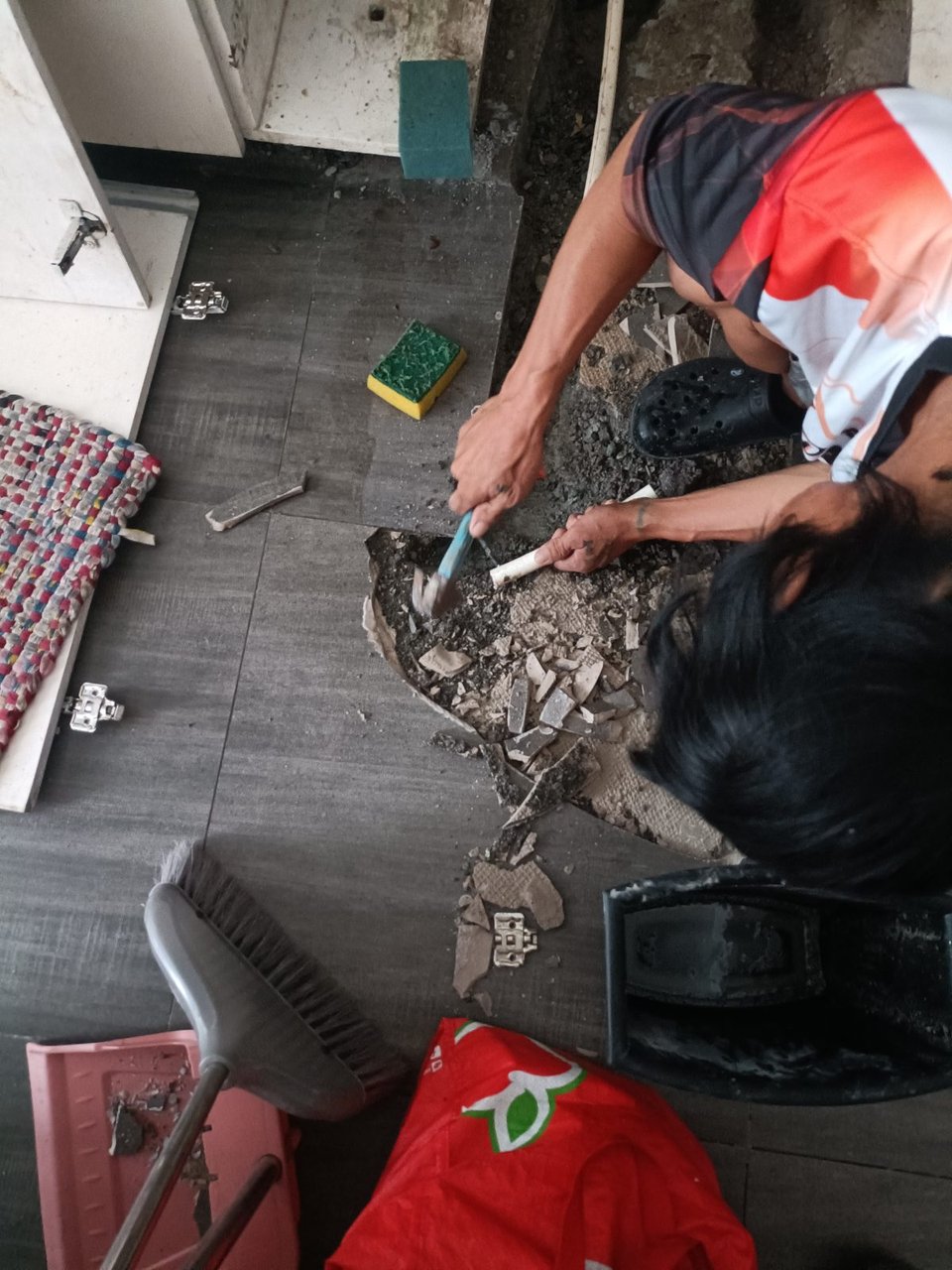A KuyaYos mason chiseling out broken floor tiles before replacing them